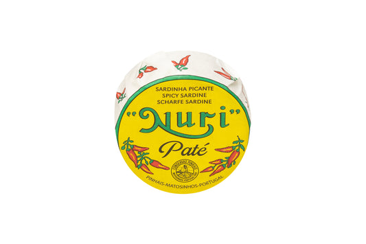 Die runde gelbe Dose „Nuri“ PIKANTE SARDINENPATÈ MIT OLIVENÖL mit leuchtend roten Chili-Illustrationen fängt die feurige Essenz von Piri-Piri ein und spiegelt seinen Ursprung in einem traditionellen portugiesischen Fischrestaurant wider.