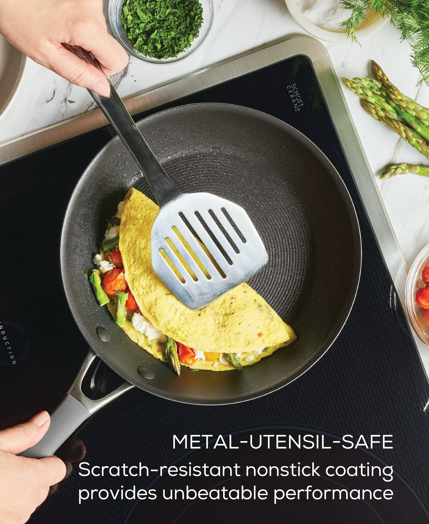 Ein Pfannenwender wendet ein Omelett in einer Pfanne BRATPFANNE CIRCULON A1 SERIE - VERSCHIEDENE GRÖSSEN von Circulon auf dem Herd, umgeben von frischen Kräutern und Gemüse.