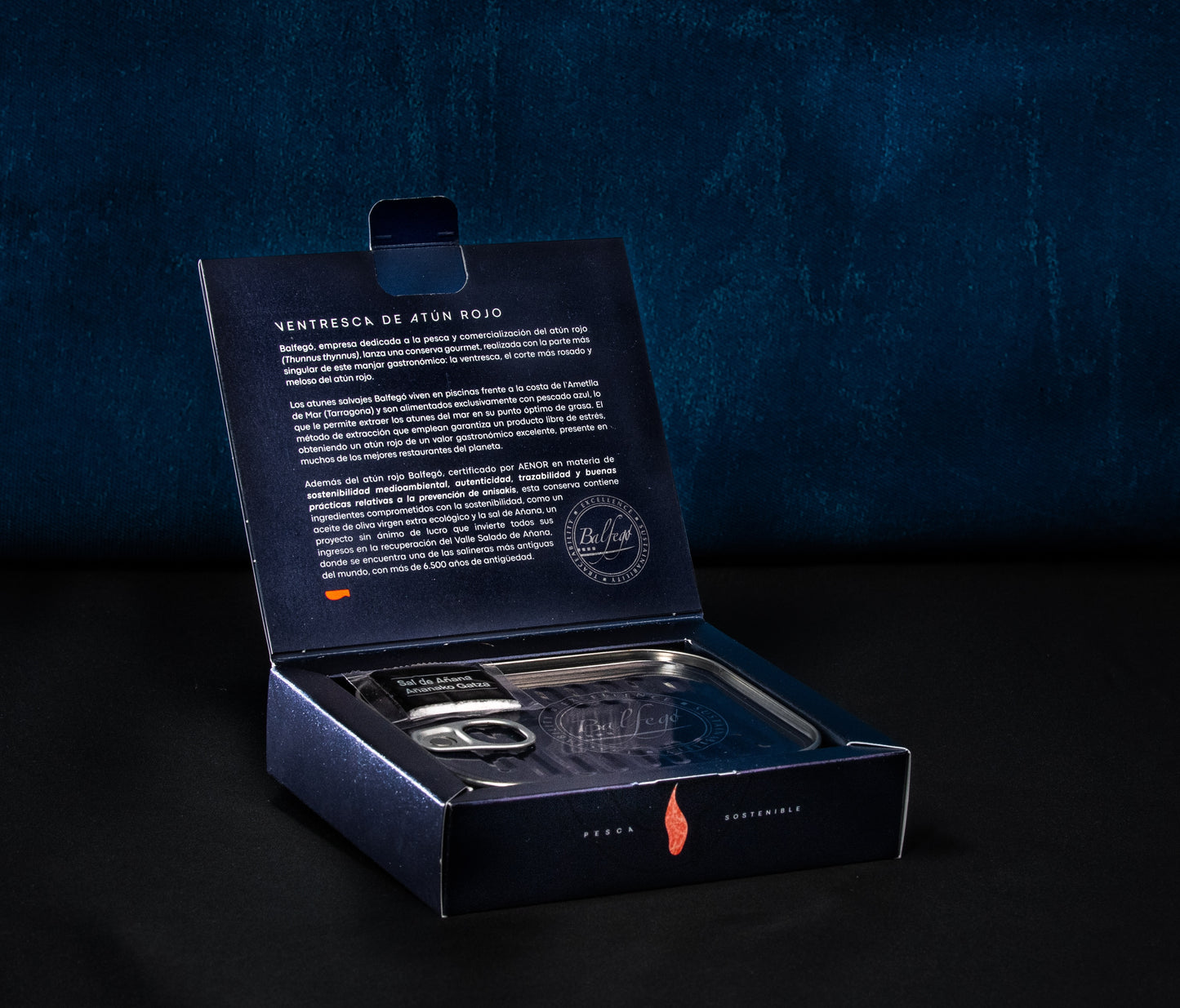 Öffnen Sie die Box „BALFEGO-THUNFISCHBAUCH IN OLIVENÖL“ auf schwarzem und blauem Hintergrund und unterstreichen Sie Balfegos Engagement für nachhaltigen Fang.