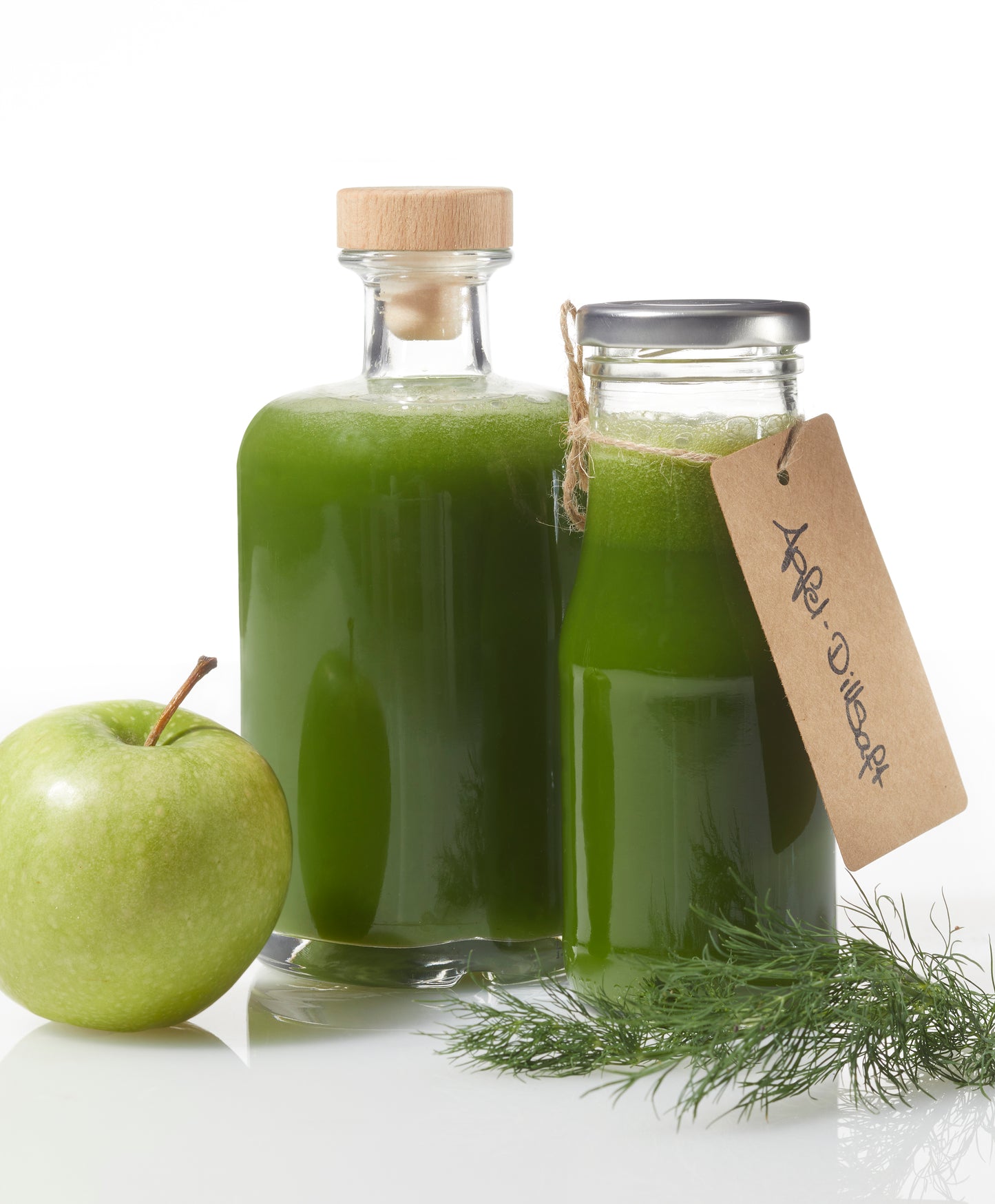 Zwei Gläser Apfel-Dillsaft von Rittmeyers Besondere Raffinessen stehen neben einem frischen grünen Apfel und Dillzweigen. Auf dem Etikett steht „Apfel Dillsoft“ – ein Hinweis auf Aromen, die begeistern und gleichzeitig das Immunsystem stärken.