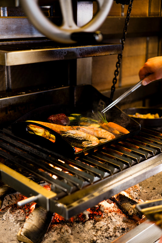 Grillen Sie gemischte Meeresfrüchte und Gemüse mit einer Zange über offener Flamme auf der robusten Kockums Jernverk GRIDDLEPLATTE KOCKUMS 35 X 35 CM.