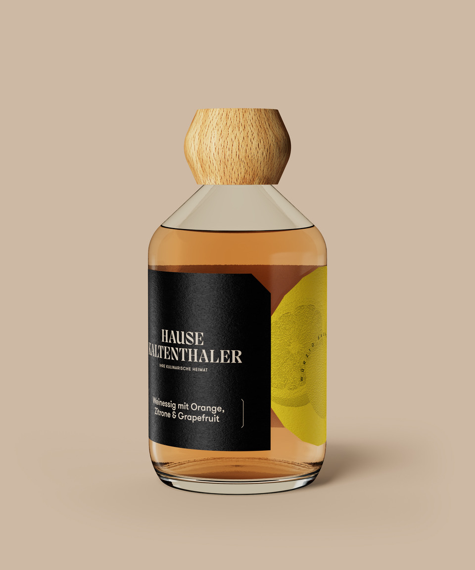 Eine braune Flasche mit Holzverschluss und der Aufschrift „Hause Kaltenthaler“ zeigt ein lebendiges Design mit frischen Zitrusfrüchten wie Orange, Zitrone und Grapefruit und deutet auf die spritzige Note hin, die sich perfekt für Salatdressings eignet.
