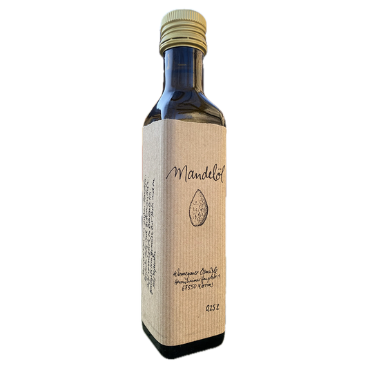 Eine Flasche mit der Aufschrift „MANDEL-ÖL kalt gepresst“ von Wonnegauer Ölmühle und goldenem Verschluss ist mit einer handgezeichneten Mandel und einem handgeschriebenen Text versehen, der den reichhaltigen Fettgehalt hervorhebt.