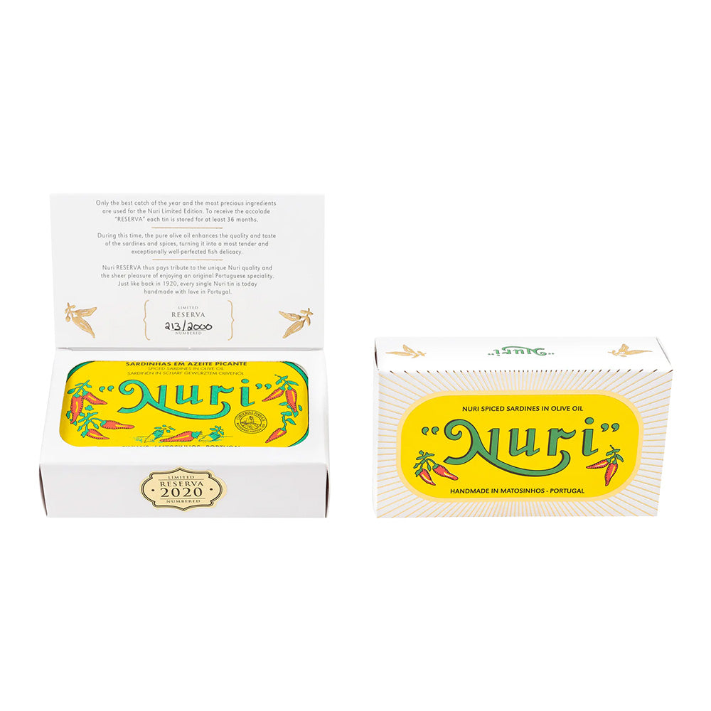 Eine geöffnete Schachtel enthüllt eine Dose NURI PIKANTE JAHRGANGS-SARDINEN RESERVA 2020 in Olivenöl mit leuchtend gelber Verpackung – ein Beweis für die exquisite portugiesische Konservenproduktion.