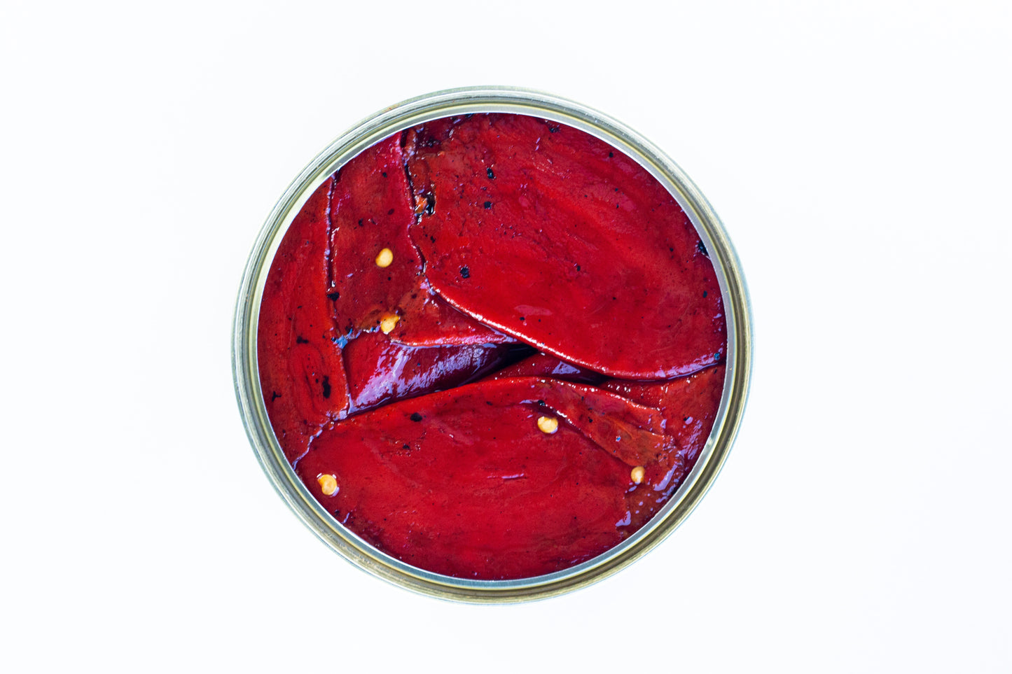 Draufsicht auf geschnittene EINGELEGTE PIQUILLO-PAPRIKA mit Samen, angeordnet in einem runden Glas vor weißem Hintergrund. Marke: El Carrascal.