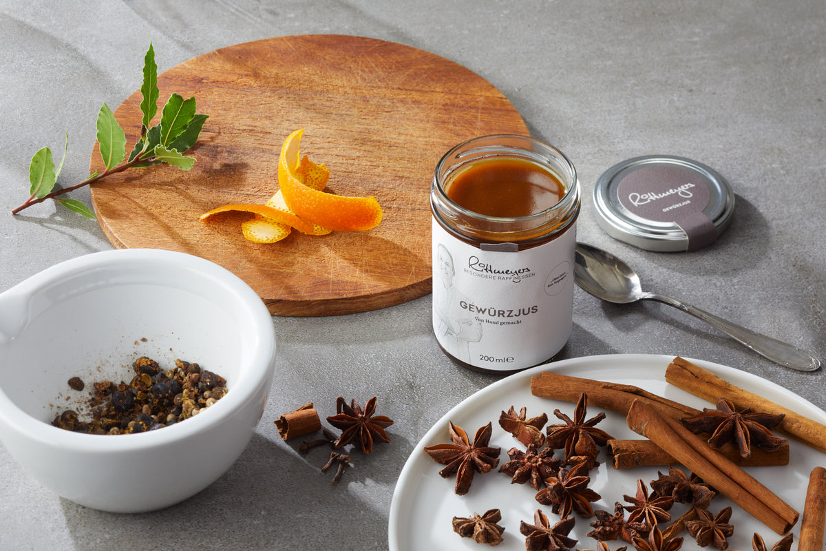 Glas Gewürzjus von Jens Rittmeyer mit Orangenschale, Sternanis, Zimtstangen und Gewürzen im Mörser